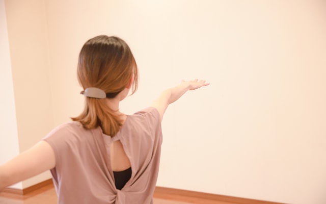 手を前後に広げたヨガのポーズをする女性