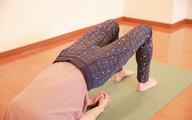 マットの上で仰向けになって腰を上げる女性