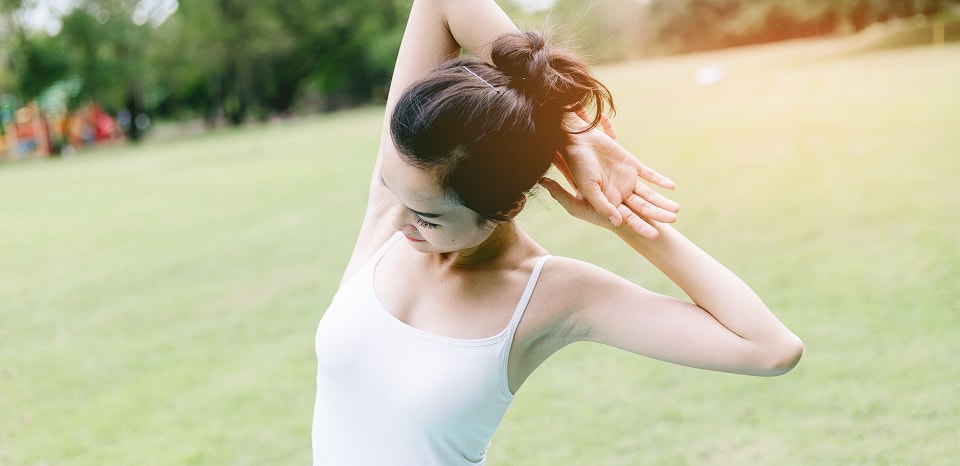 屋外で腕を後ろにストレッチする女性